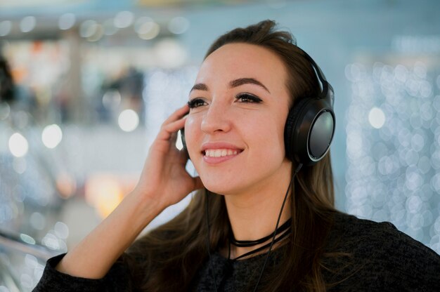 Close-up smiling woman holding headphones on head in shopping mall