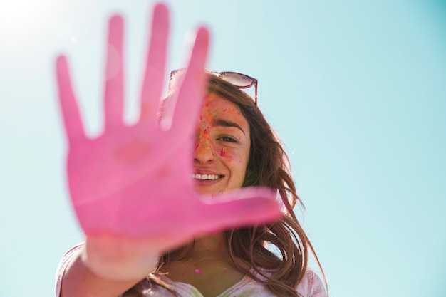 Close-up of a smiling young woman showing her painted pink hand