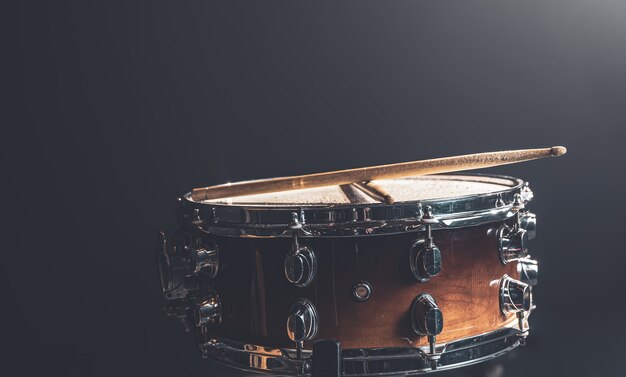 Close-up, snare drum, percussion instrument against a dark background with stage lighting.