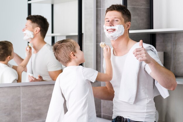 Close-up of a son helping his father for shaving beard showing thumb up sign