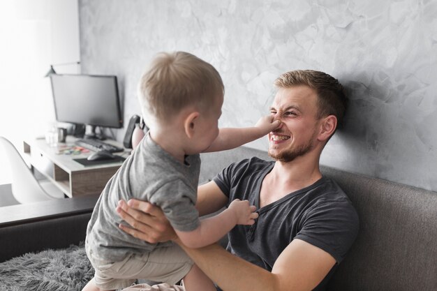 Close-up of son holding his father's nose while playing with him