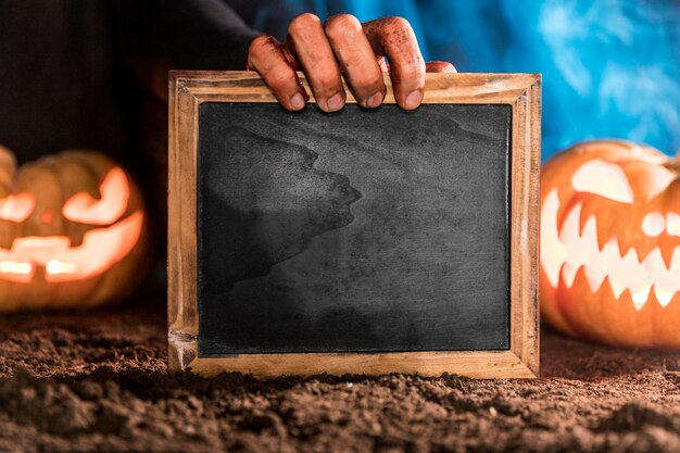 Close-up spooky hand holding blackboard