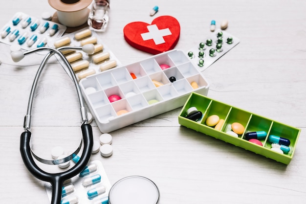 Free photo close-up stethoscope near pills and heart with cross