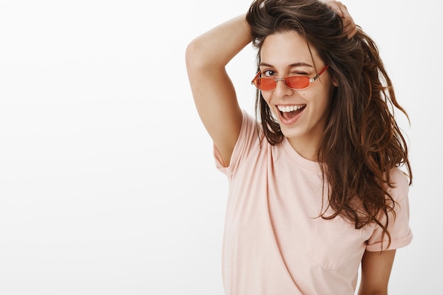 Close-up of stylish girl with sunglasses posing against the white wall