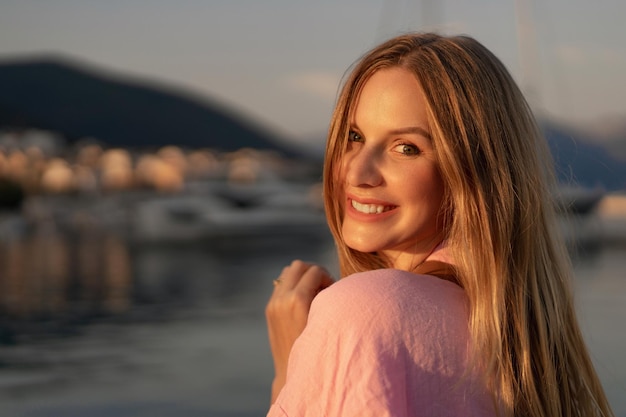 Close up sunny portrait of pretty blonde owmn posing near sea at sunset.