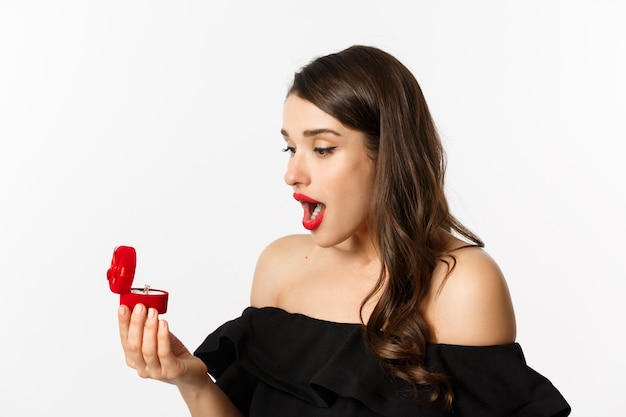 Close-up of surprised woman open box with engagement ring, looking amazed, receiving marriage proposal, girlfriend getting married.