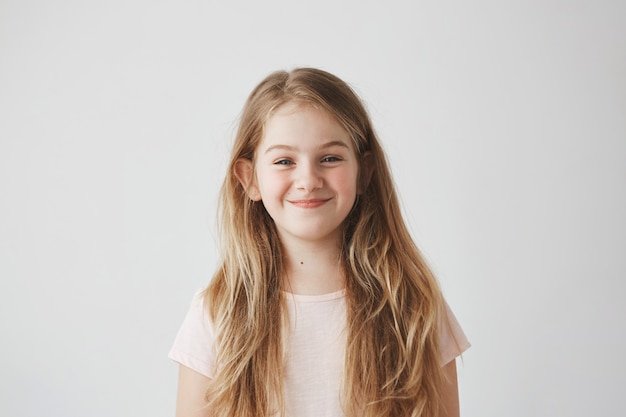 Close up of sweet little girl with light long hair and red cheeks  with foxy expression, going to make something bad.