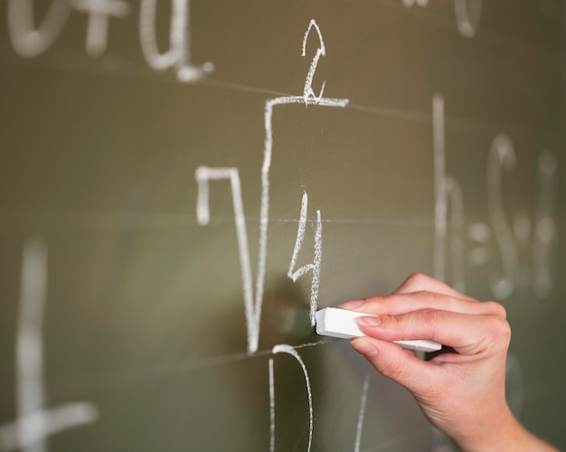 Free photo close-up teacher writing on chalkboard