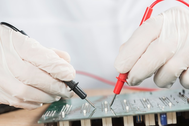 Free Photo close-up of a technician hand examining computer circuit board with digital multimeter