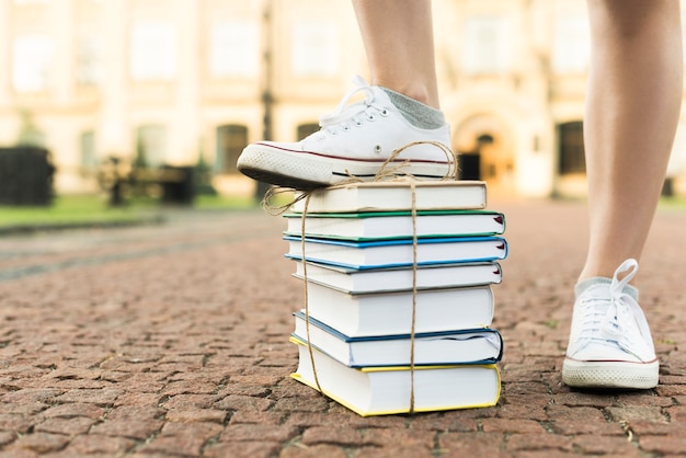 Free photo close up of teenage girl stepping on books