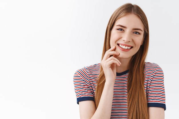 Close-up tender, feminine young happy girl in striped t-shirt, long chestnut hair, smiling toothy, tilt head entertained, touch cheek slightly with cute gaze, having pleasant conversation