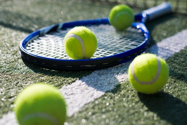 Close-up tennis racket and balls on the ground