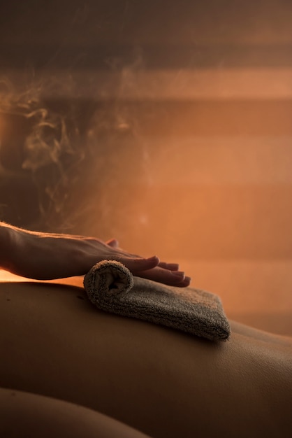 Free photo close-up of a therapist hand massaging woman's back with hot towel in spa