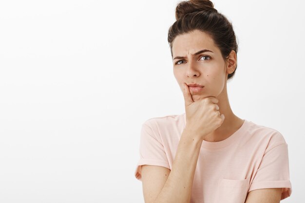 Close-up of thoughtful girl posing against the white wall