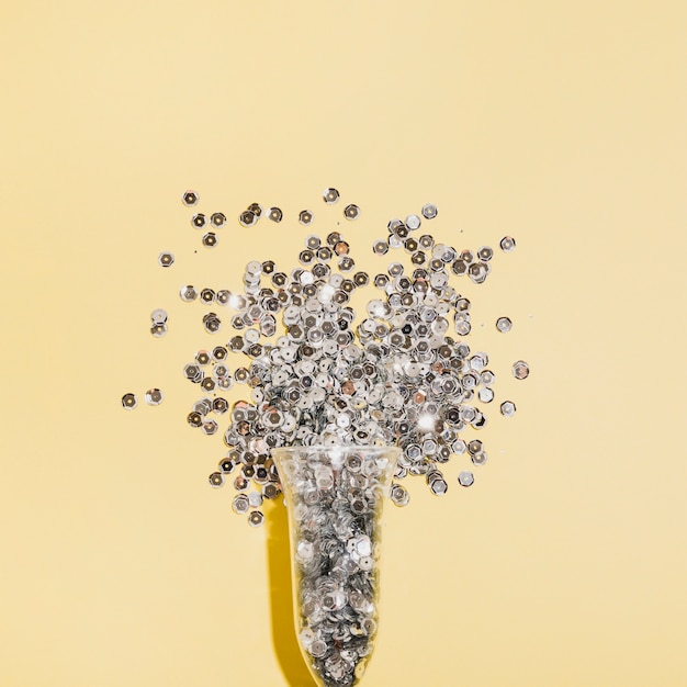 Free Photo close-up top view glass of champagne filled with silver sequins