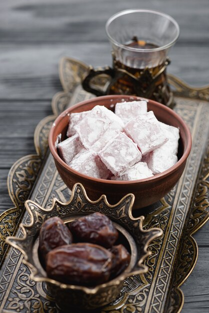 Close-up of traditional turkish delight lukum; dates and tea on metallic tray