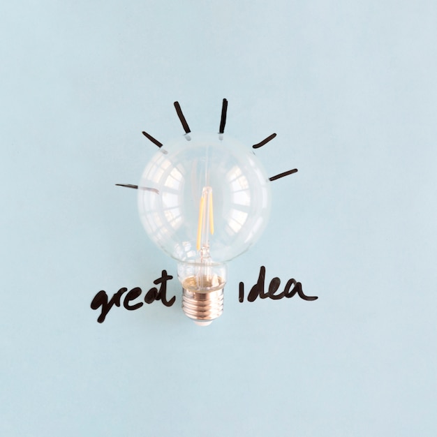 Free Photo close-up of transparent light bulb with great idea word on blue backdrop