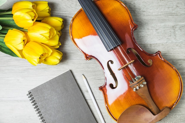 Close-up of tulips; diary; pencil and violin on wooden background