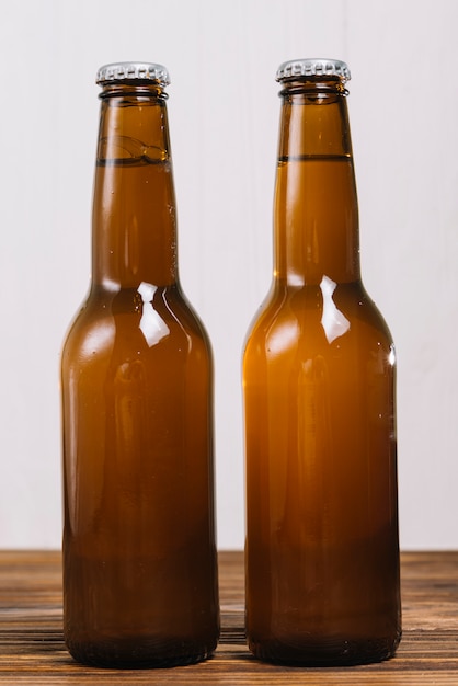 Free photo close-up of two beer bottles on wooden table top