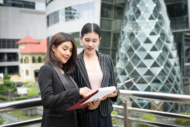 Close up of two Business woman looking with paper document together while walking to office. Business people concept.