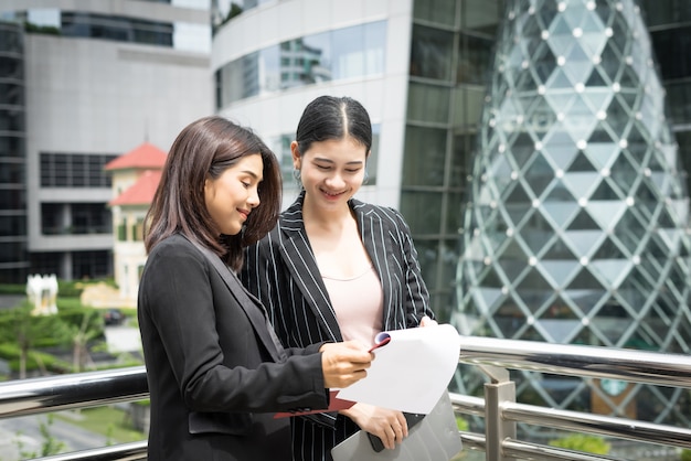 Close up of two Business woman looking with paper document together while walking to office. Business people concept.