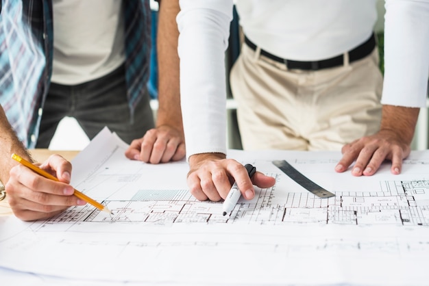 Free Photo close-up of two male architect's hand over blueprint