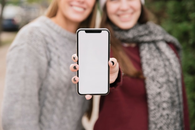 Close up two smiling women holding phone in hands