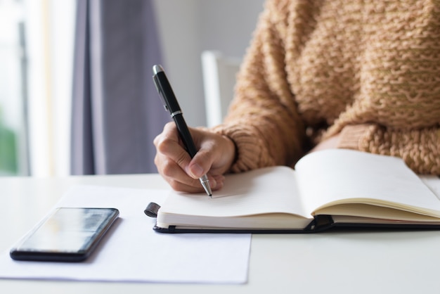 Close-up of unrecognizable lady making notes