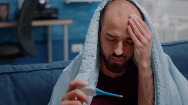 Free Photo close up of unwell adult looking at thermometer