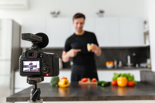 Free photo close up of a video camera filming smiling male blogger