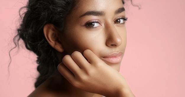 Close up video of a happy and relaxed young woman with perfect olive skin fixing her wavy black hair isolated on white