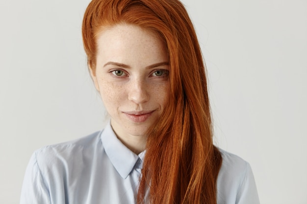 Close up view of beautiful happy Caucasian woman with ginger hair and freckles looking and smiling