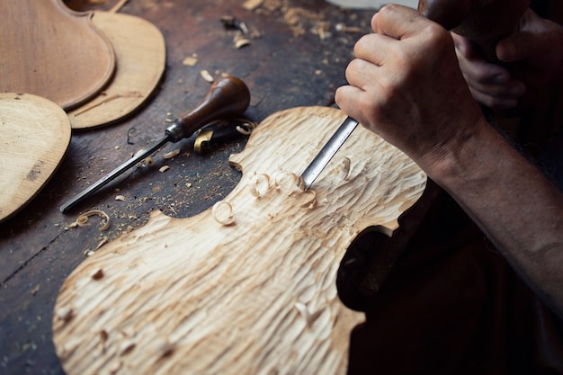 Free photo close up view of carpenter's hands shaping and carving wood in his old-fashion workshop