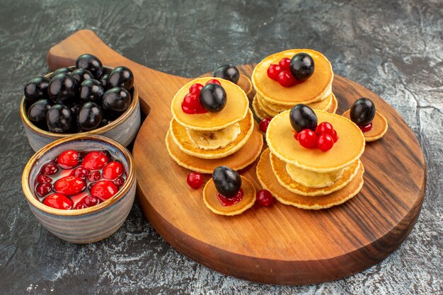 Close up view of classic buttermilk pancakes served with fruits on gray