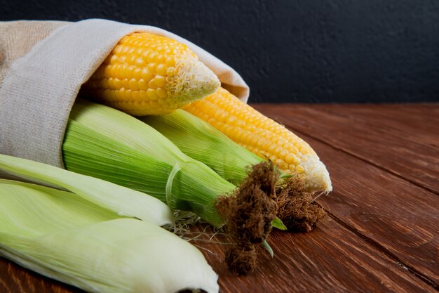 Close-up view of cooked and uncooked corns in sack on wooden surface 2