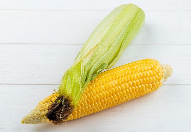 Free photo close-up view of cooked and uncooked corns on wooden surface