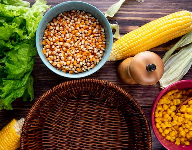 Close-up view of corn seeds with lettuce corns and empty basket on wooden table