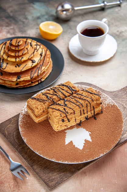 Close up view of delicious desserts and a cup of tea lemon and cinnamon on colourful table