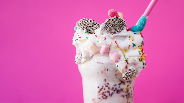 Close-up view of delicious milkshake with pink background