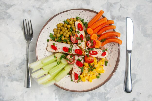 Close up view of delicious salad with various ingredients on a plate and cutlery set on white surface with free space