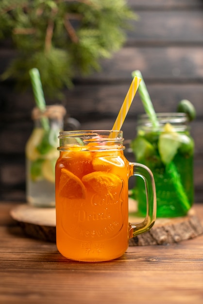 Close up view of detox water and fresh juice in bottles with tubes on brown wooden background