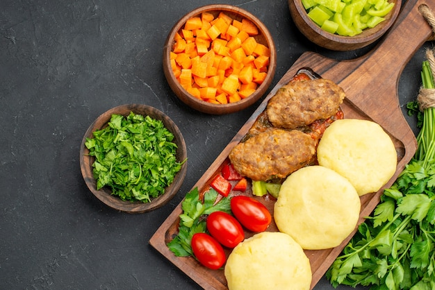 Free Photo close up view of dinner with tasty cutlets vegetables and greens on dark