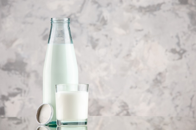 Free photo close up view of glass bottle and cup filled with milk cap on pastel colors background with free space