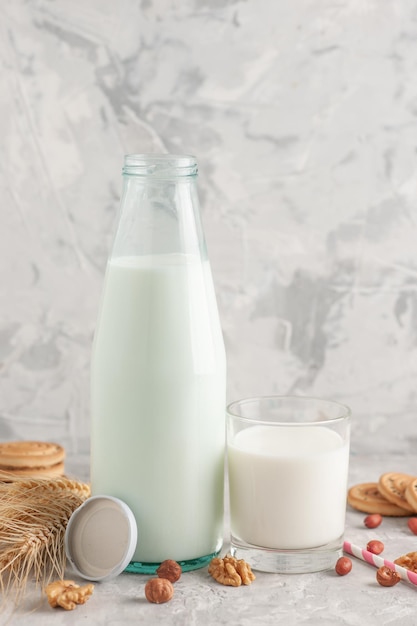 Close up view of glass cup bottle filled with milk cap and cookies spikes peanuts walnut candy on stained white surface