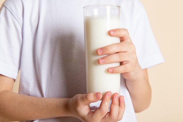 close up, view little kid holding glass of milk in white t-shrit