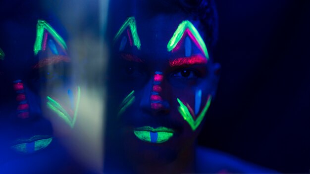 Close-up view of man with colorful fluorescent make-up