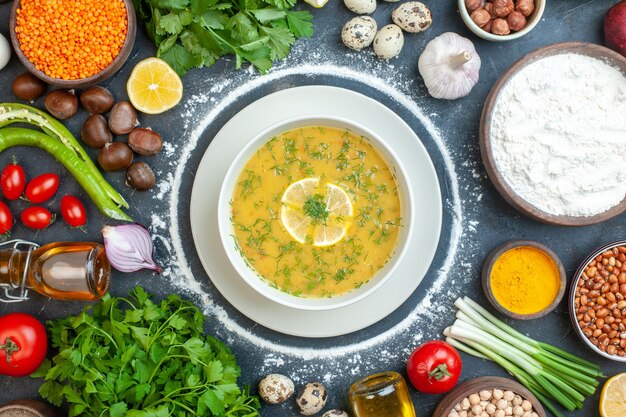 Free Photo close up view of mouth-watering soup served with lemon and green in a white bowl and flour tomato oil bottle flour green bundles eggs on dark