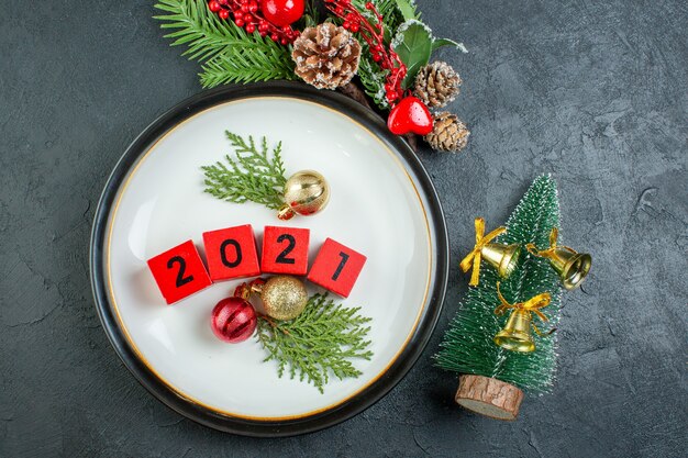 Close up view of numbers decoration accessories on a plate fir branches conifer cone on dark background