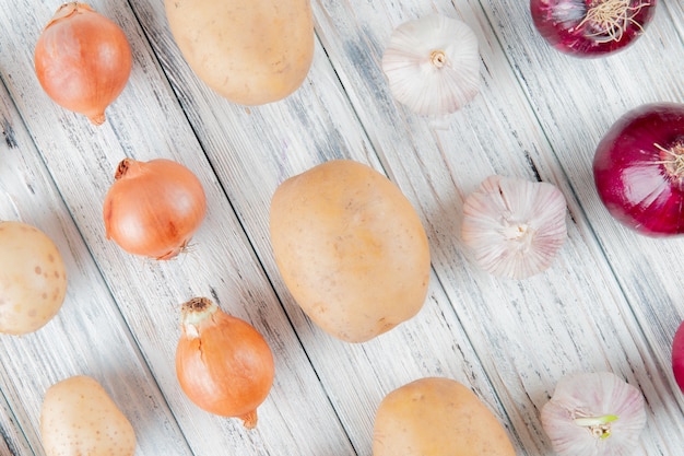 Close up view of pattern of vegetables as onion garlic potato on wooden background