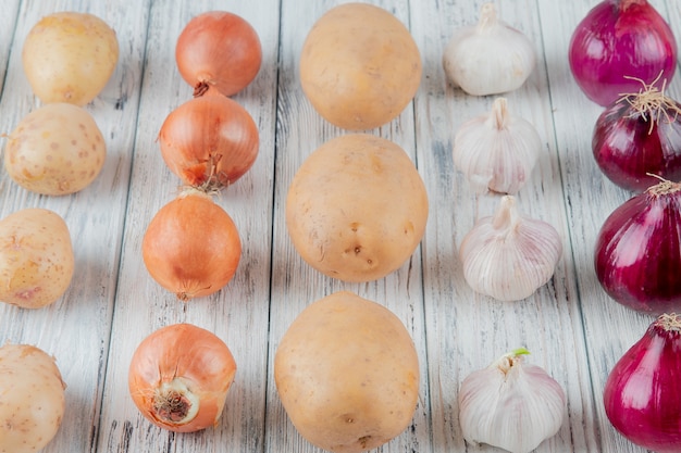 Close up view of pattern of vegetables as onion potato garlic on wooden background